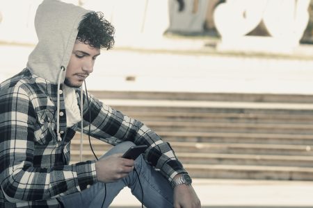 young stylish bearded man in Hoodie checkered shirt listening music in the city
